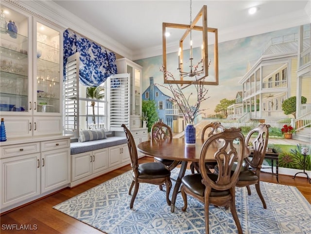 dining area featuring a chandelier, wallpapered walls, crown molding, and wood finished floors