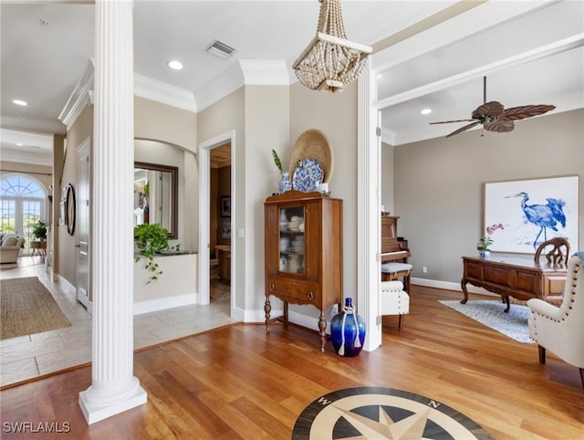 entrance foyer featuring visible vents, wood finished floors, crown molding, and ornate columns