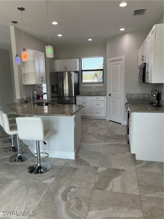 kitchen featuring open shelves, visible vents, appliances with stainless steel finishes, a sink, and a peninsula