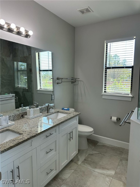 full bath featuring visible vents, a stall shower, a sink, and toilet