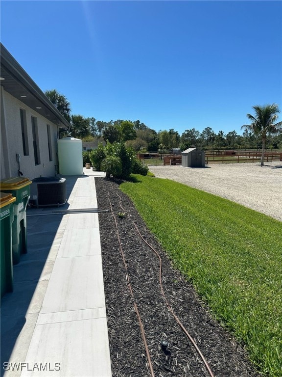 view of yard with an outbuilding, cooling unit, fence, and a storage shed