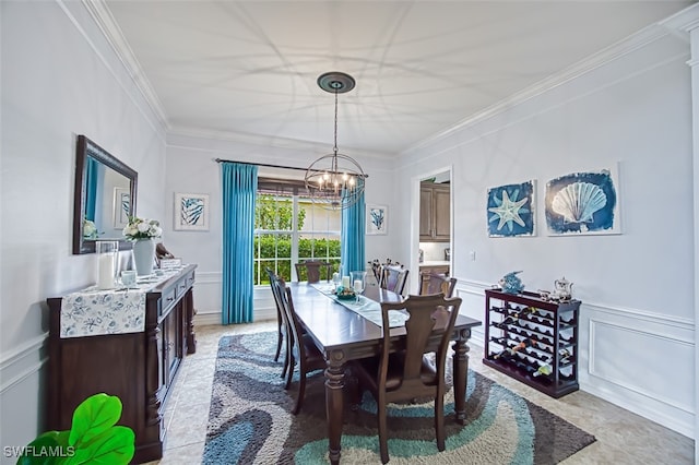 dining room with a wainscoted wall, a chandelier, crown molding, and a decorative wall