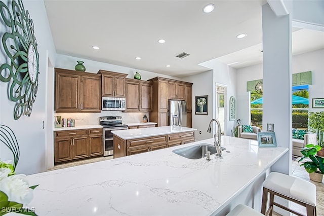 kitchen with visible vents, a kitchen island, recessed lighting, appliances with stainless steel finishes, and a sink