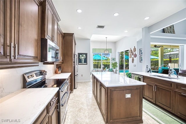 kitchen with visible vents, a sink, appliances with stainless steel finishes, a wealth of natural light, and a center island