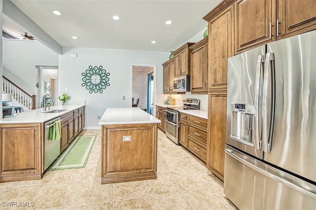 kitchen with a kitchen island, light countertops, brown cabinets, stainless steel appliances, and a sink