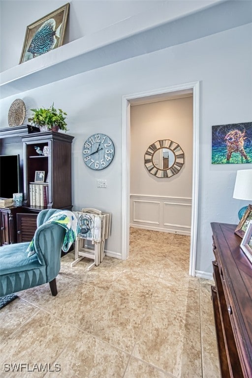 sitting room with a decorative wall and a wainscoted wall