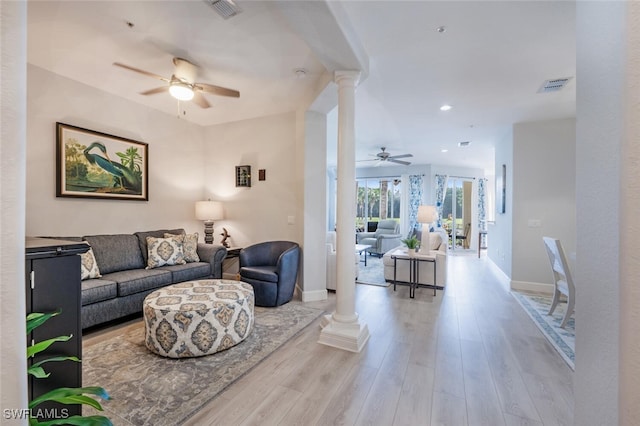 living area with visible vents, wood finished floors, decorative columns, and baseboards