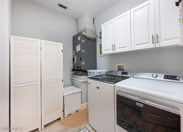 clothes washing area with cabinet space, visible vents, independent washer and dryer, heating unit, and light wood-style floors