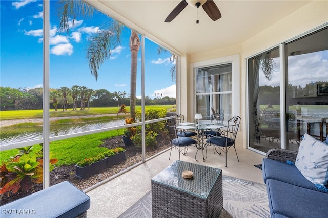 sunroom with a water view, a ceiling fan, and a healthy amount of sunlight