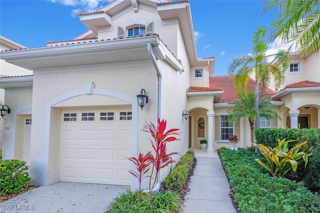 view of front of house featuring an attached garage, driveway, a tile roof, and stucco siding