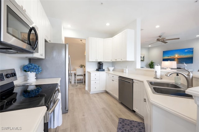 kitchen with white cabinets, light wood finished floors, stainless steel appliances, and a sink