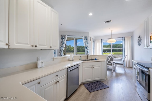 kitchen with white cabinets, light wood-type flooring, stainless steel appliances, and a sink