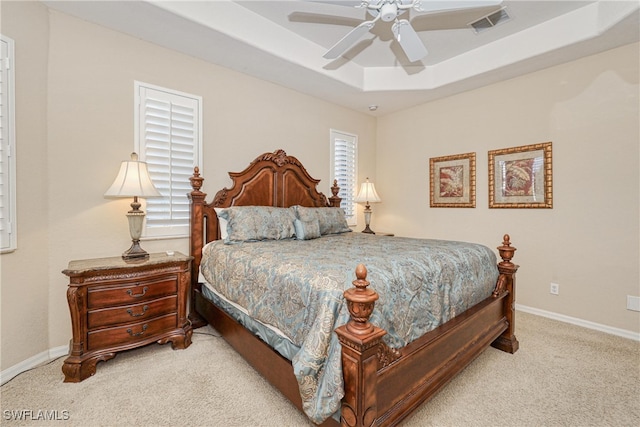 carpeted bedroom with visible vents, multiple windows, baseboards, and a tray ceiling