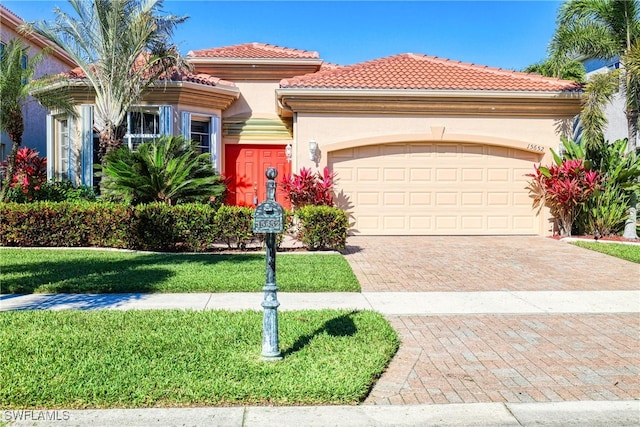 mediterranean / spanish home with a front yard, an attached garage, stucco siding, a tiled roof, and decorative driveway