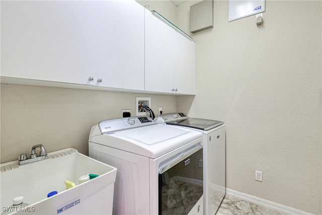 laundry area featuring baseboards, washer and dryer, a textured wall, cabinet space, and a sink