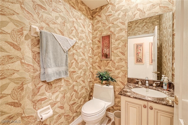 half bathroom with toilet, vanity, and wallpapered walls