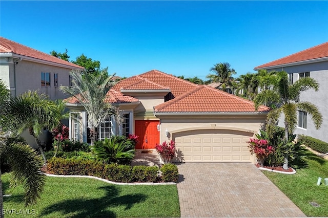 mediterranean / spanish-style home with an attached garage, stucco siding, a front lawn, a tile roof, and decorative driveway