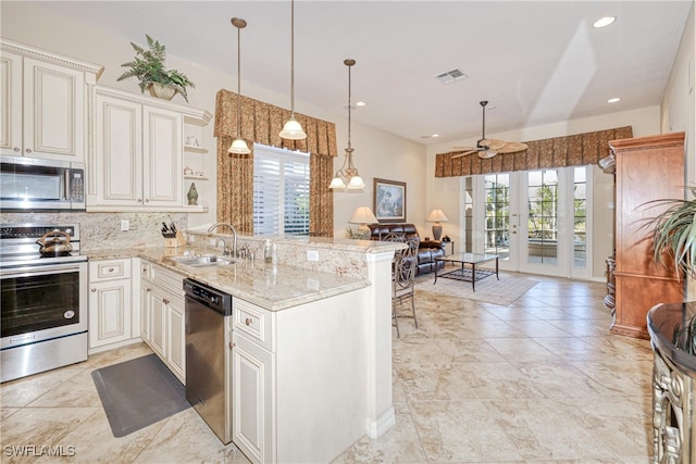 kitchen with visible vents, decorative backsplash, appliances with stainless steel finishes, a peninsula, and a sink