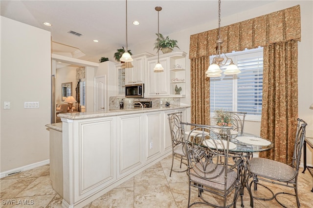 kitchen featuring stainless steel microwave, backsplash, decorative light fixtures, a peninsula, and open shelves