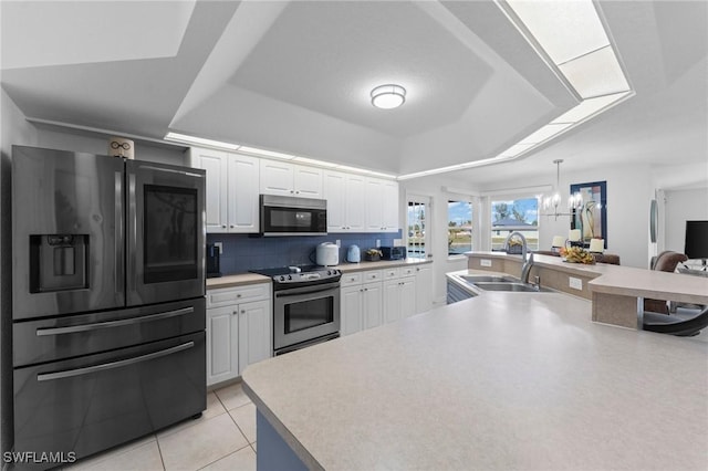 kitchen featuring a notable chandelier, stainless steel appliances, a sink, white cabinetry, and tasteful backsplash