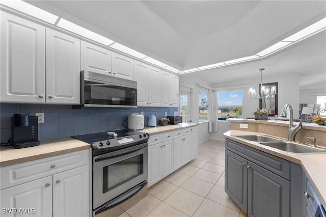 kitchen with light tile patterned floors, a sink, white cabinets, appliances with stainless steel finishes, and decorative backsplash