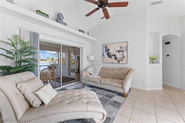 tiled living room featuring arched walkways, high vaulted ceiling, visible vents, baseboards, and a ceiling fan