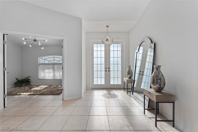 doorway to outside featuring baseboards, french doors, light tile patterned flooring, and an inviting chandelier