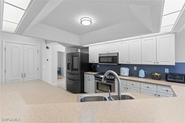 kitchen featuring tasteful backsplash, light countertops, black fridge with ice dispenser, and a sink