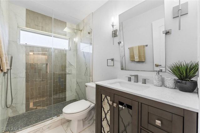 bathroom featuring toilet, marble finish floor, a marble finish shower, and vanity