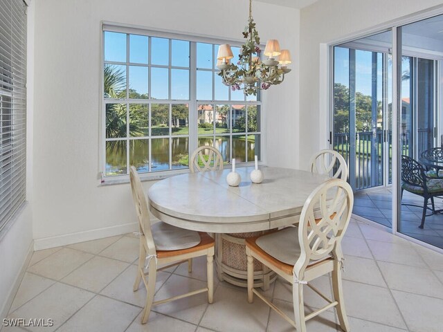dining space featuring light tile patterned flooring, baseboards, a notable chandelier, and a water view