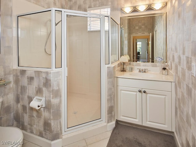 full bath with a stall shower, toilet, vanity, and tile walls