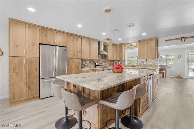 kitchen featuring tasteful backsplash, a kitchen island, light stone countertops, appliances with stainless steel finishes, and wall chimney exhaust hood