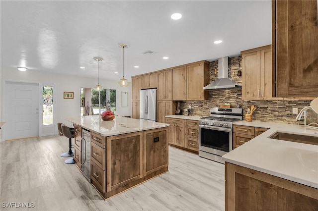 kitchen with a sink, wall chimney range hood, tasteful backsplash, and stainless steel appliances