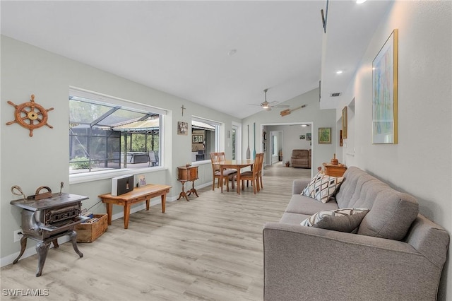 living room featuring light wood finished floors, visible vents, baseboards, vaulted ceiling, and a ceiling fan