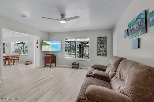 living area with baseboards, light wood-style floors, and a ceiling fan