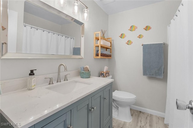 full bathroom with baseboards, toilet, wood finished floors, and vanity