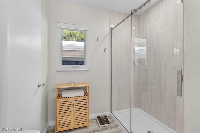 full bathroom with a shower stall, baseboards, and wood finished floors