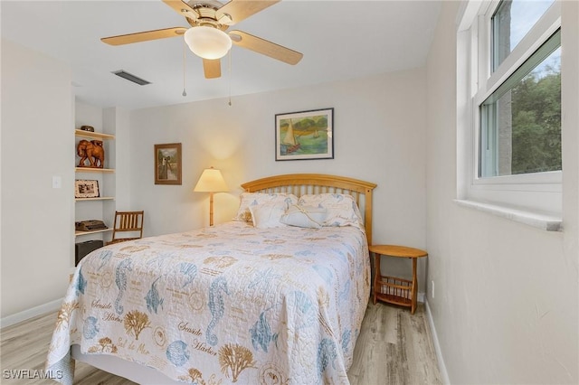 bedroom with wood finished floors, visible vents, and baseboards