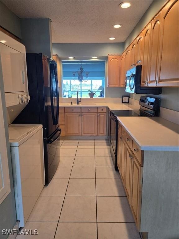5910 Via Delray Blvd Unit B, Delray Beach, FL 33484 - kitchen with black appliances, estacked washer and dryer, light tile patterned floors, light countertops, and a textured ceiling