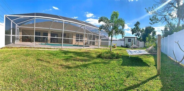 rear view of house with a fenced in pool, a lawn, glass enclosure, a fenced backyard, and a patio area