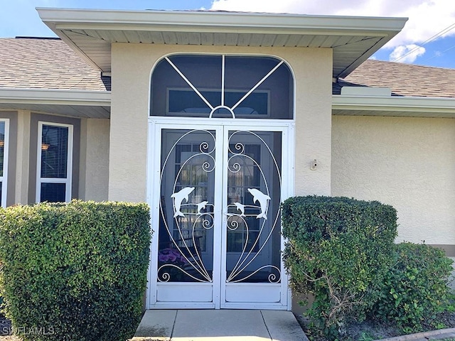 doorway to property with french doors, roof with shingles, and stucco siding