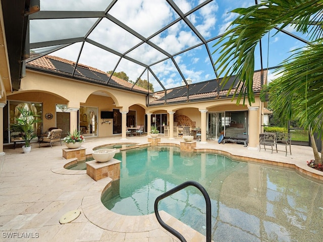 outdoor pool with an in ground hot tub, a patio, and glass enclosure