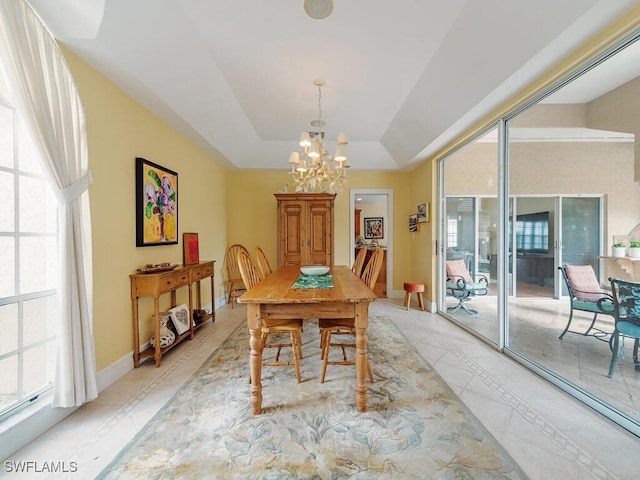 dining space with a chandelier, a raised ceiling, a wealth of natural light, and baseboards