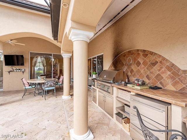 view of patio featuring outdoor dining space, ceiling fan, and area for grilling