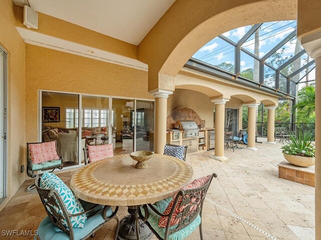 view of patio featuring a lanai, outdoor dining area, an outdoor kitchen, and area for grilling