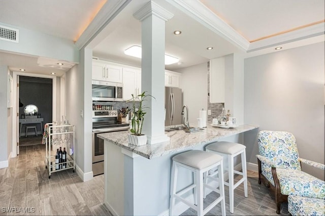 1085 Forest Lakes Dr Unit 8105, Naples, FL 34105 - kitchen with light stone counters, a breakfast bar, visible vents, appliances with stainless steel finishes, and white cabinetry