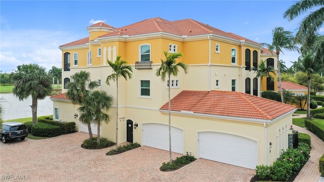 mediterranean / spanish-style home featuring a garage, a tiled roof, and stucco siding