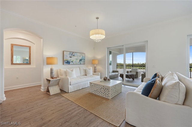 living area with an inviting chandelier, crown molding, baseboards, and wood finished floors