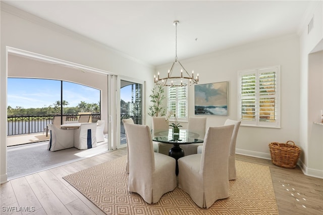 dining room featuring light wood-style flooring, a notable chandelier, visible vents, baseboards, and ornamental molding