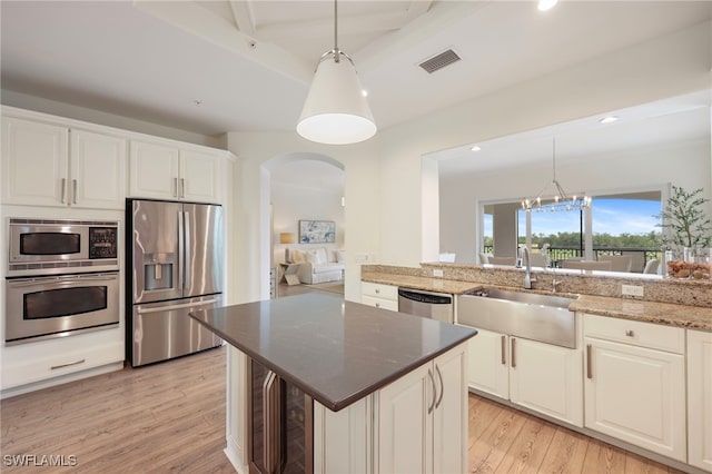 kitchen with arched walkways, visible vents, stainless steel appliances, light wood-type flooring, and a sink